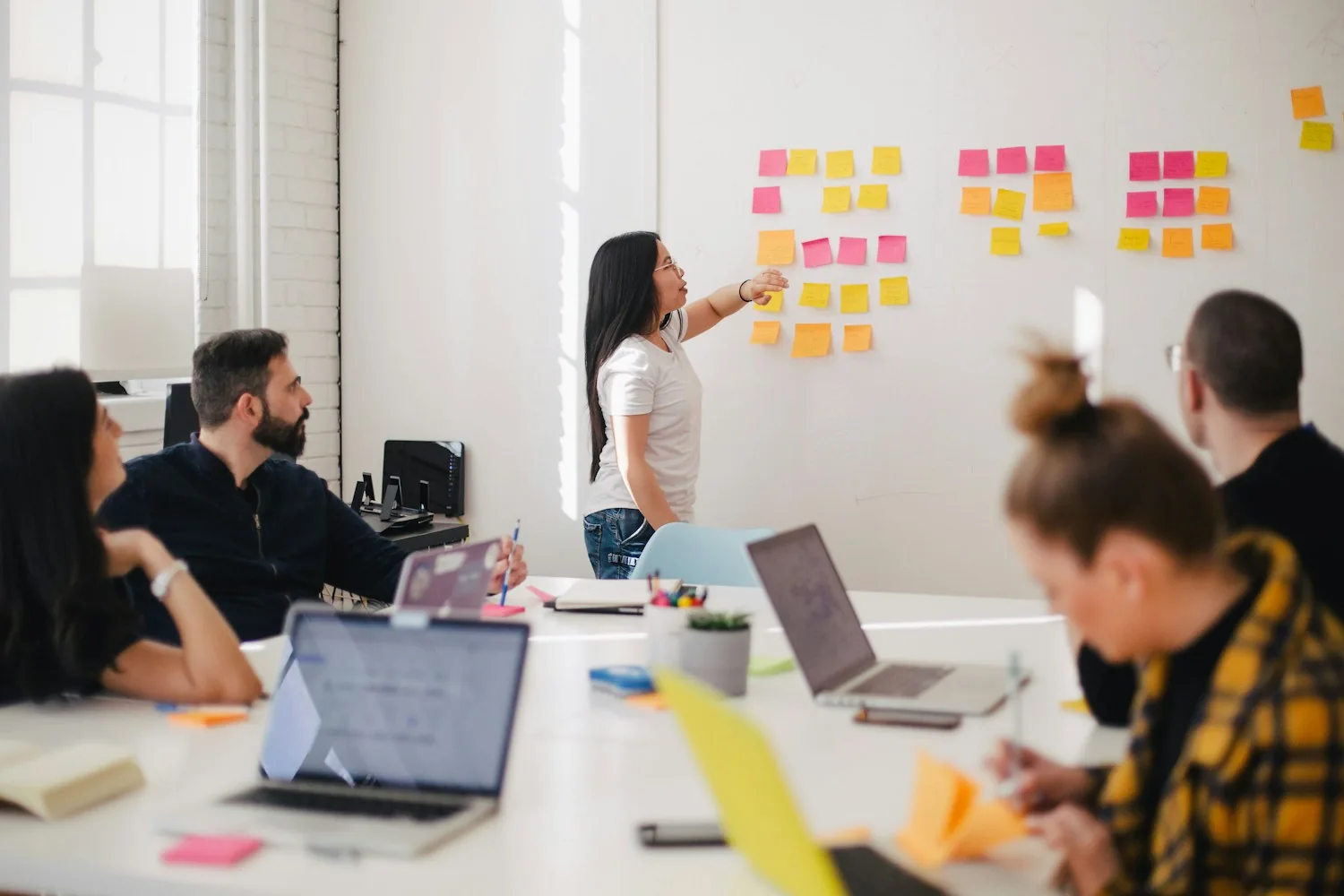 Marketing presenter leading a workshop beside a whiteboard with sticky notes
